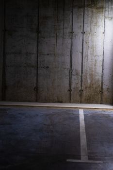 Empty parking lot with overhead dim light, underground parking garage.