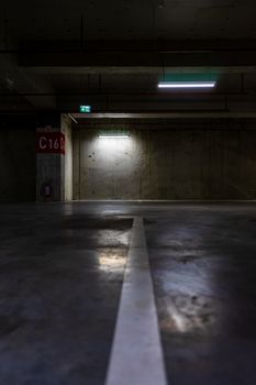 Empty parking lot with overhead dim light, underground parking garage.