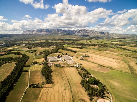 Aerial view of farm field with big farm in South of France. Big farm land during summer dry season next the mountain.