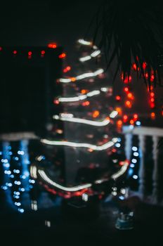 Decorated Christmas tree on the street close-up. Red balls and garland backlit with lanterns. New Year's baubles macro photo with bokeh. Winter holiday light decoration