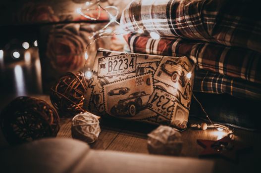 gifts packed in boxes and wrapped with festive paper lie under a Christmas tree in the warm light from the LED garland. The concept of winter holidays.