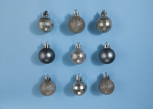 Metallic color Christmas balls on a blue paper. Festive symmetry flat lay.