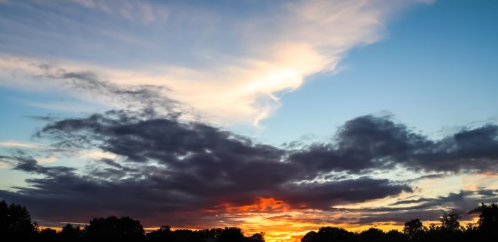 Beautiful panorama of orange and yellow clouds at sunrise and sunset in a blue sky