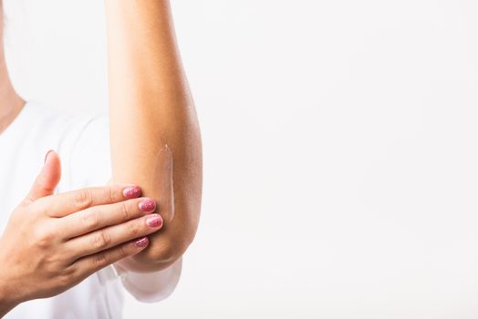 Closeup young Asian woman applies lotion cream on her elbow, studio shot isolated on white background, Healthcare medical and hygiene skin body care concept