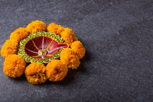 Top view overhead clay lit Diya or oil lamp and yellow flower, studio shot on concrete background, Decoration of Hinduism rangoli, Happy Deepavali or Diwali festival concept