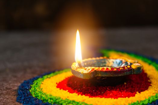 Close up clay lit light a fire already on Diya or oil lamp on concrete background, Decoration of Hinduism rangoli, Happy celebration Deepavali, or Diwali Indian festival concept