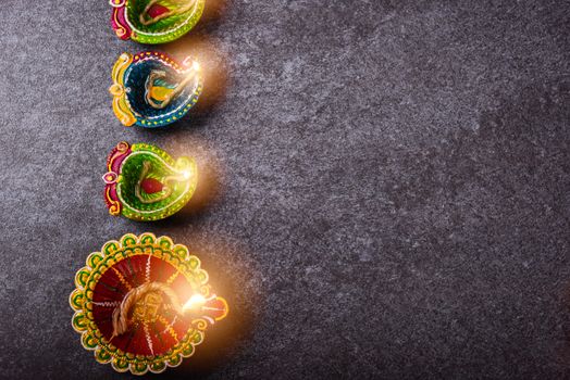 Top view overhead clay lit light a fire already on Diya or oil lamp, studio shot on concrete background, Decoration of Hinduism rangoli, Happy celebration Deepavali or Diwali festival concept