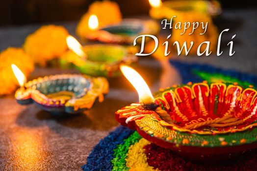 Close up clay lit light a fire already on Diya or oil lamp with flowers on concrete background, Decoration of Hinduism rangoli, Happy celebration Deepavali, or Diwali Indian festival concept