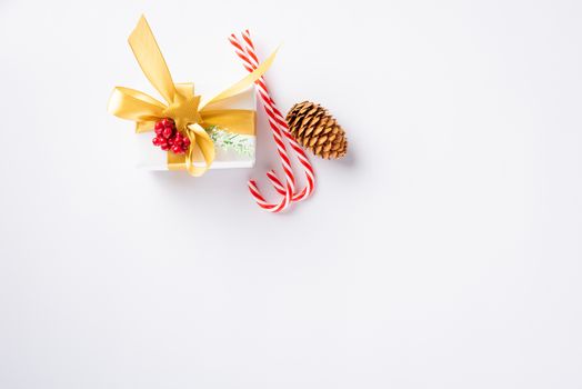 Christmas holiday composition top view flat lay of with a gift box and gold ribbon, fir branches, pine cones, and candy with copy space isolated on white background, New year day concept
