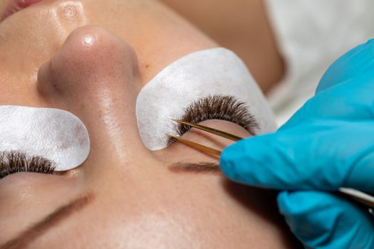 Treatment beauty procedure of upgrade Eyelashes Extension with tweezers Woman Eyes with long extended lashes
