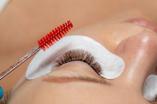 Close Woman Eye with Eyelashes Extension with eyepatch under eye and brush for care after beauty treatment closeup stock photo