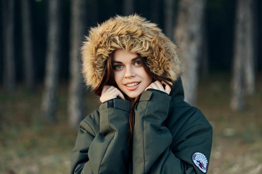 Woman in a jacket with a hood on her head close-up coolness on the background of the forest. High quality photo