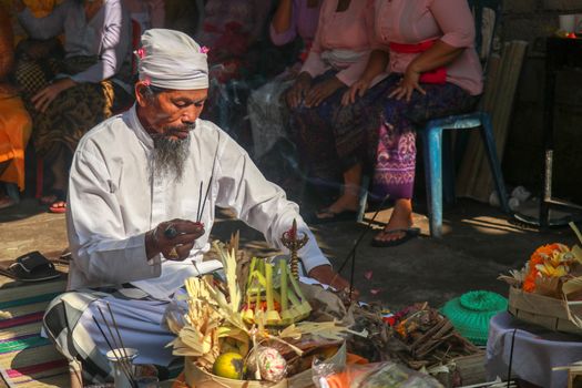 Hindu priest wearing a white uniform was carrying out a religious ceremony with a melodious chime and a beautiful and peaceful chant.