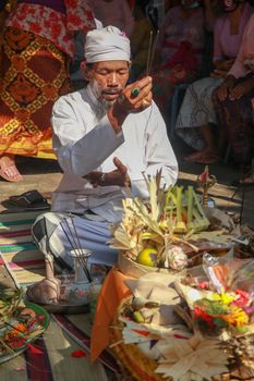 Front view to hindu priest during ceremony. Pedanda sits in front of the sacrifices and performs wedding ceremonies.
