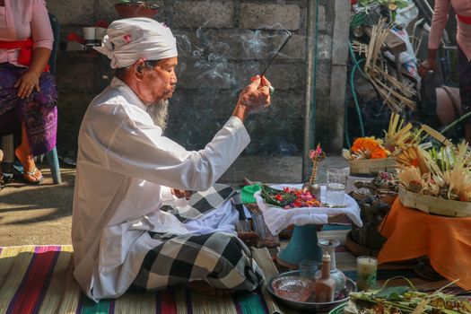 Hindu priest wearing a white uniform was carrying out a religious ceremony with a melodious chime and a beautiful and peaceful chant.