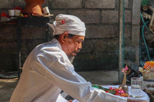 Closeup photograph of a Balinese Hindu high priest conducting a Ngaben ceremony in Ubud, Denpasar, Bali, Indonesia.