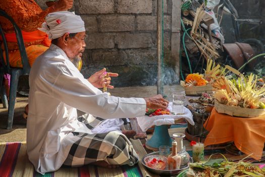 Hindu priest wearing a white uniform was carrying out a religious ceremony with a melodious chime and a beautiful and peaceful chant.