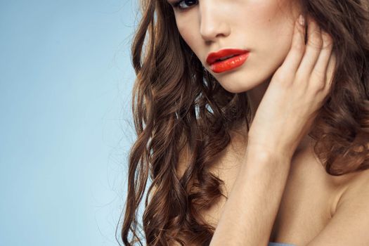 Beautiful woman naked shoulders hairstyle care bright makeup blue background. High quality photo