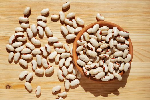 Heap of Scicli beans -Sicily -on wooden background ,creamy white cannellini -type beans with reddish spot around the hilum ,preserve biodiversity