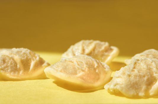 Orecchiette pasta on colored background ,a small ear shape pasta with the center thinner than the edge  and a rough surface 