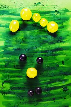 Funny face made using black and yellow grapes , the background is painted 