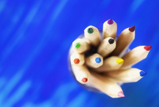 Group of sharp multicolored pencils on blue background , macro photography