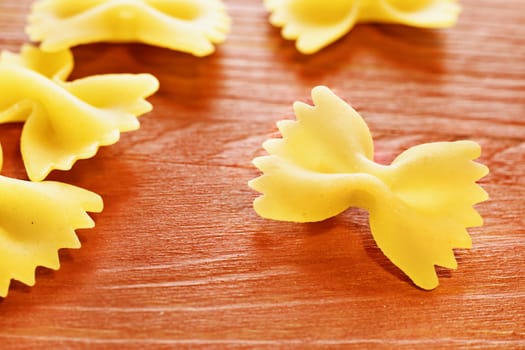 Dry italian pasta called farfalle on wooden red table , beautiful bow tie  -shape pasta 