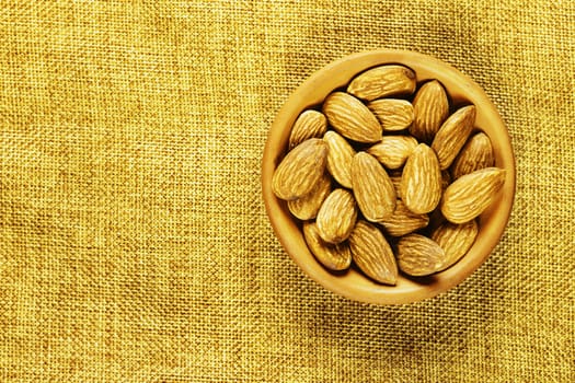 Beautiful shelled almonds in bowl on sackcloth background 