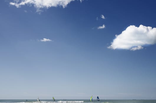 Several windsurfers at the sea -Italy -Ostia -in a bright  sunny day , in the background boats 