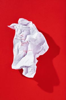 Sheet of white crumpled paper  on red background , handwritten note with red pencil -I love you - , beautiful shadow on background