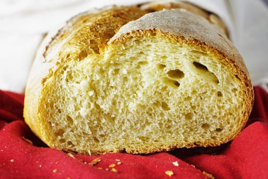 Freshy baked cut bread on red and white cloth  ,bread crumbs in the foreground ,durum wheat bread