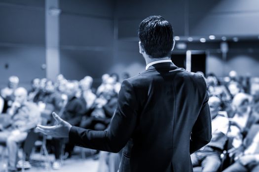 Speaker at Business Conference with Public Presentations. Audience at the conference hall. Entrepreneurship club. Rear view. Panoramic composition. Blue toned greyscale.