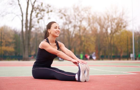 Happy girl doing fitness exercises outdoor on playground. Healthy lifestyle. Morning workout positive emotion smiling sportive people. one female training stretching