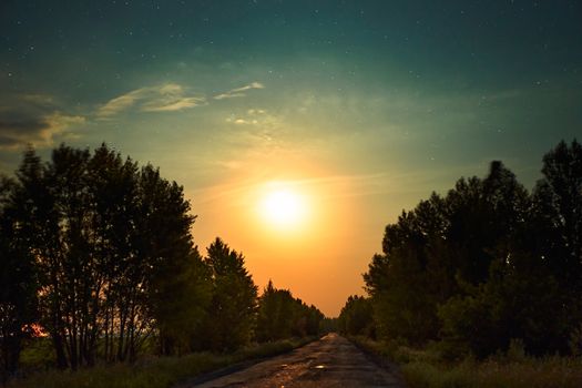 Night road with orange moon shining cloud sky galaxy stars space dust in the universe, Long exposure photograph, with grain. Summer night sky