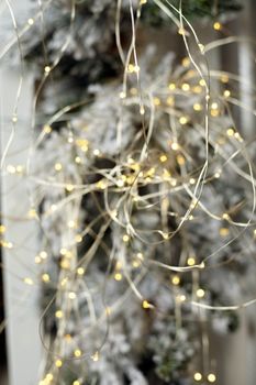 Christmas tree blur garland close-up New year background Decoration with snow and branch of Christmas tree