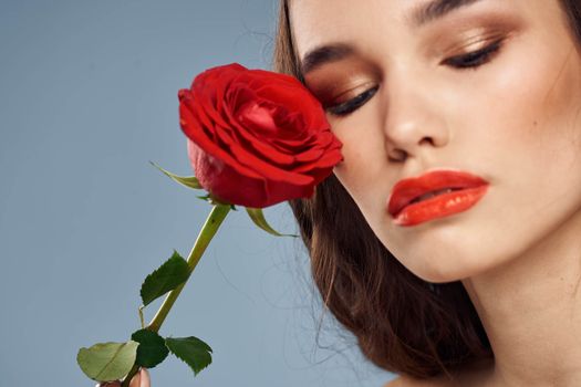 woman with a rose in her hands naked shoulders evening makeup red lips. High quality photo