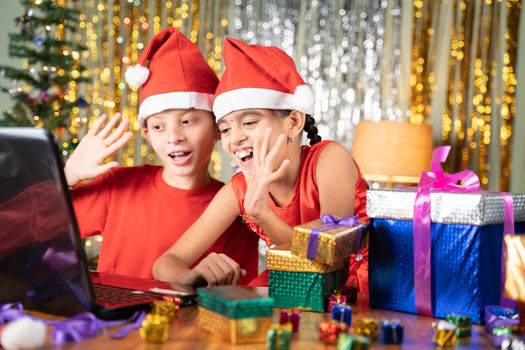 Kids got the xmas gift and Opening gift infront of Laptop on video call at home with decorated background during christmas celebration.