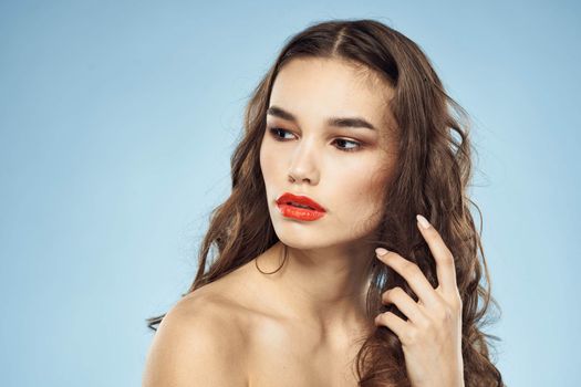 Brunette naked shoulders red lips fashionable hairstyle blue background. High quality photo