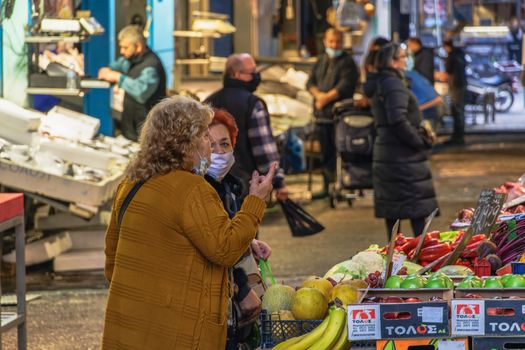 Food store with unidentified crowd wearing protective masks at Modiano enclosed market.