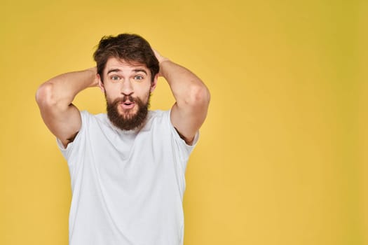 Bearded man white t-shirt emotions gestures with hands fun yellow background. High quality photo