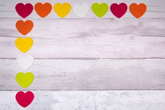 Colorful felt hearts on a background of old wooden planks resembling an old parquet floor. Concept of valentine's day and love in general.