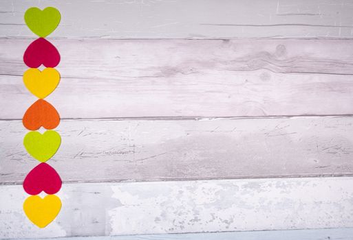 Colorful felt hearts on a background of old wooden planks resembling an old parquet floor. Concept of valentine's day and love in general.