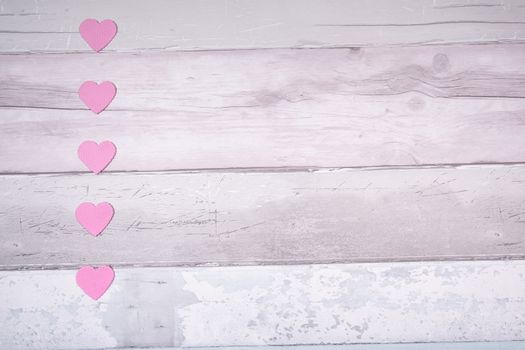 Pink felt hearts on a background of old wooden planks resembling an old parquet floor. Concept of valentines day and love in general.