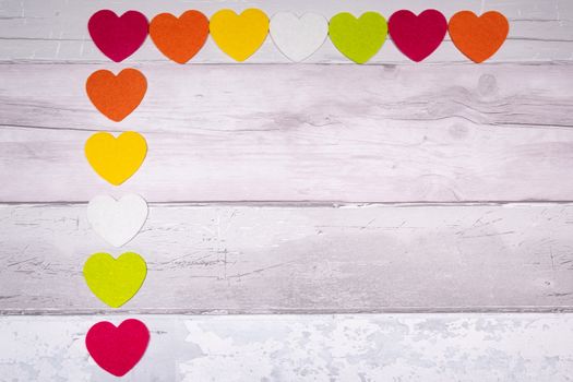 Colorful felt hearts on a background of old wooden planks resembling an old parquet floor. Concept of valentine's day and love in general.