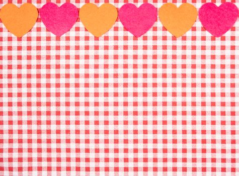 background with red and white Vichy fabric for Valentine's Day with pink and orange hearts. valentines day concept.