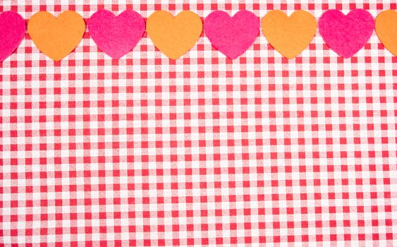 background with red and white Vichy fabric for Valentine's Day with pink and orange hearts. valentines day concept.