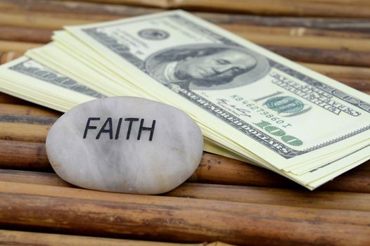 An affirmation stone with the word faith used in conjunction with a stack of money for financial concepts.