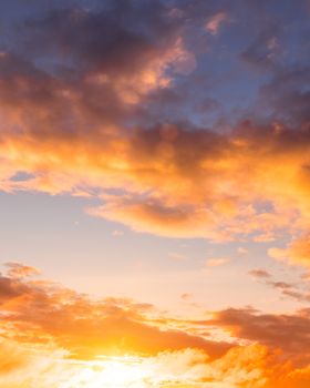 Colorful orange-purple dramatic clouds lit by the setting sun against the evening sunset sky. Cloudscape.