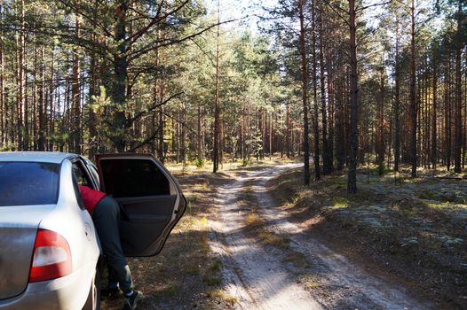 open car on the side of a dirt forest road.