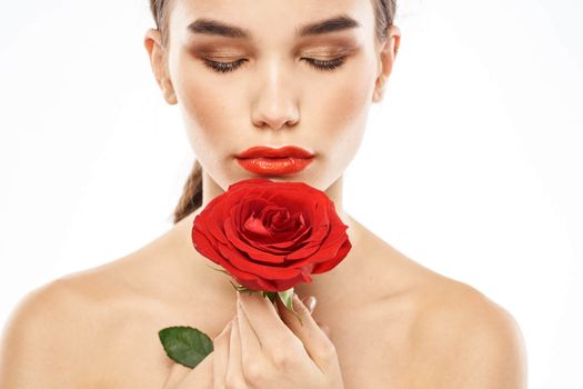 Beautiful woman with red rose near face makeup naked shoulders portrait. High quality photo